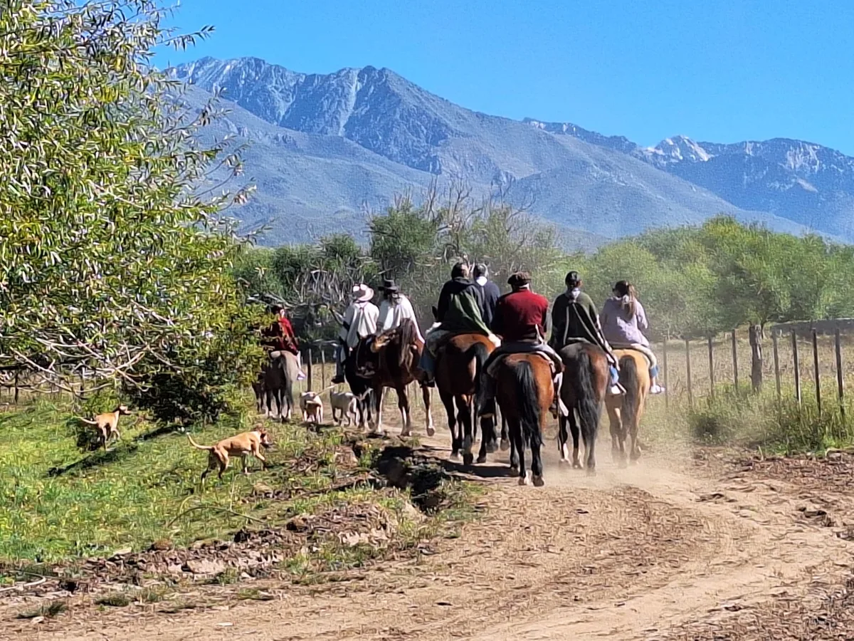 Cabalgata por un sendero de montaña con la cordillera al fondo