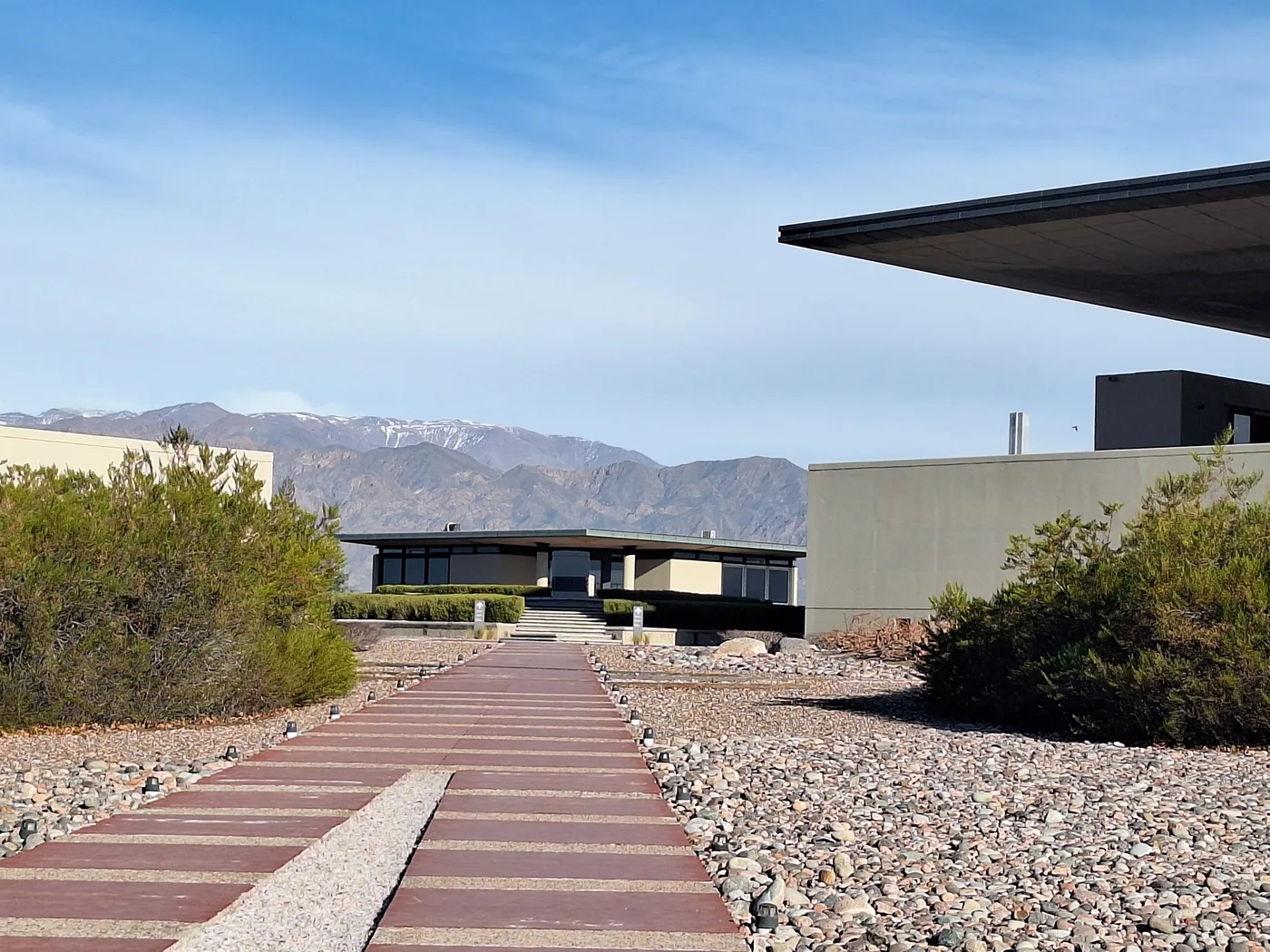 Arquitectura de bodega con techo voladizo, entre viñedos y la cordillera de los Andes