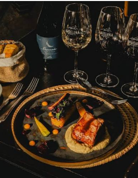 Plato gourmet de cena con copas de vino, luz cálida
